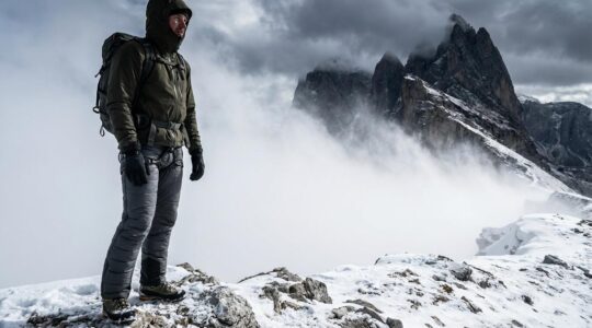 Randonneur équipé en montagne face aux éléments avec vêtements techniques multicouches